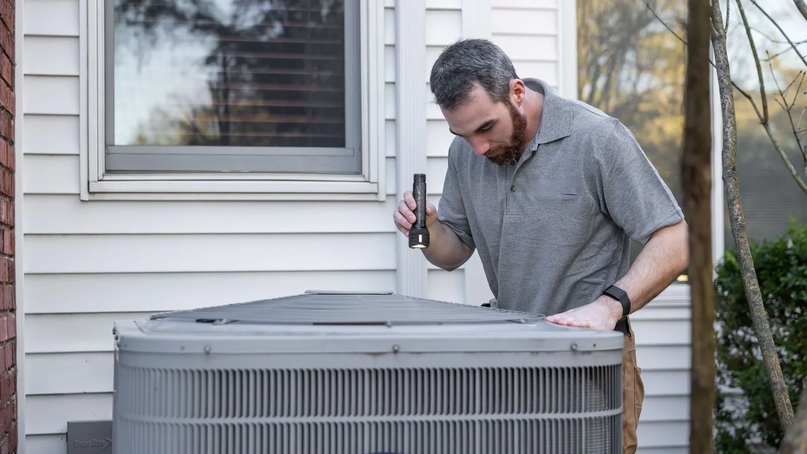 HVAC technician inspecting an outdoor air conditioning condenser unit